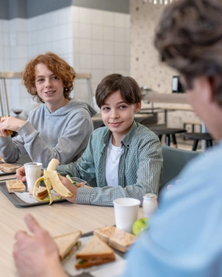 Zwei Kinder essen in der Schulmensa ihr Mittagessen.